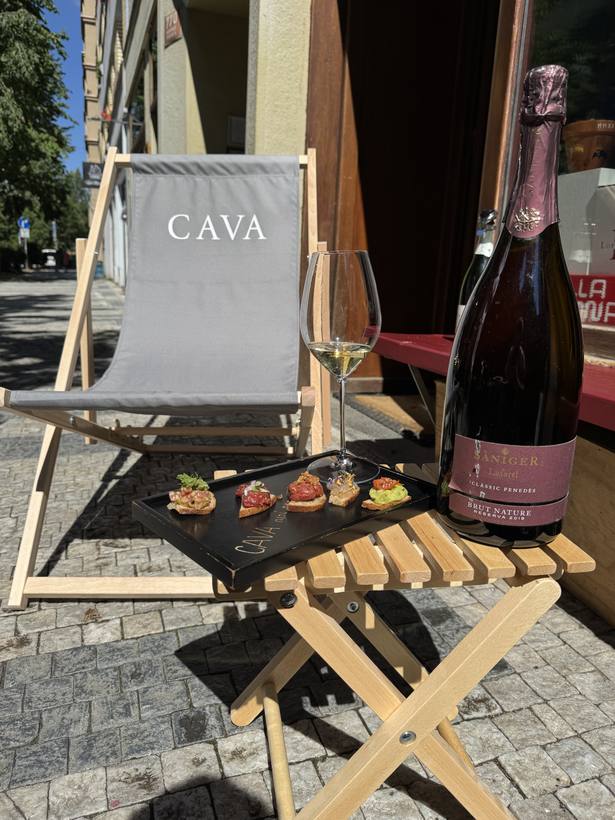 Lehátko s logem CAVA a lahev růžového na terase